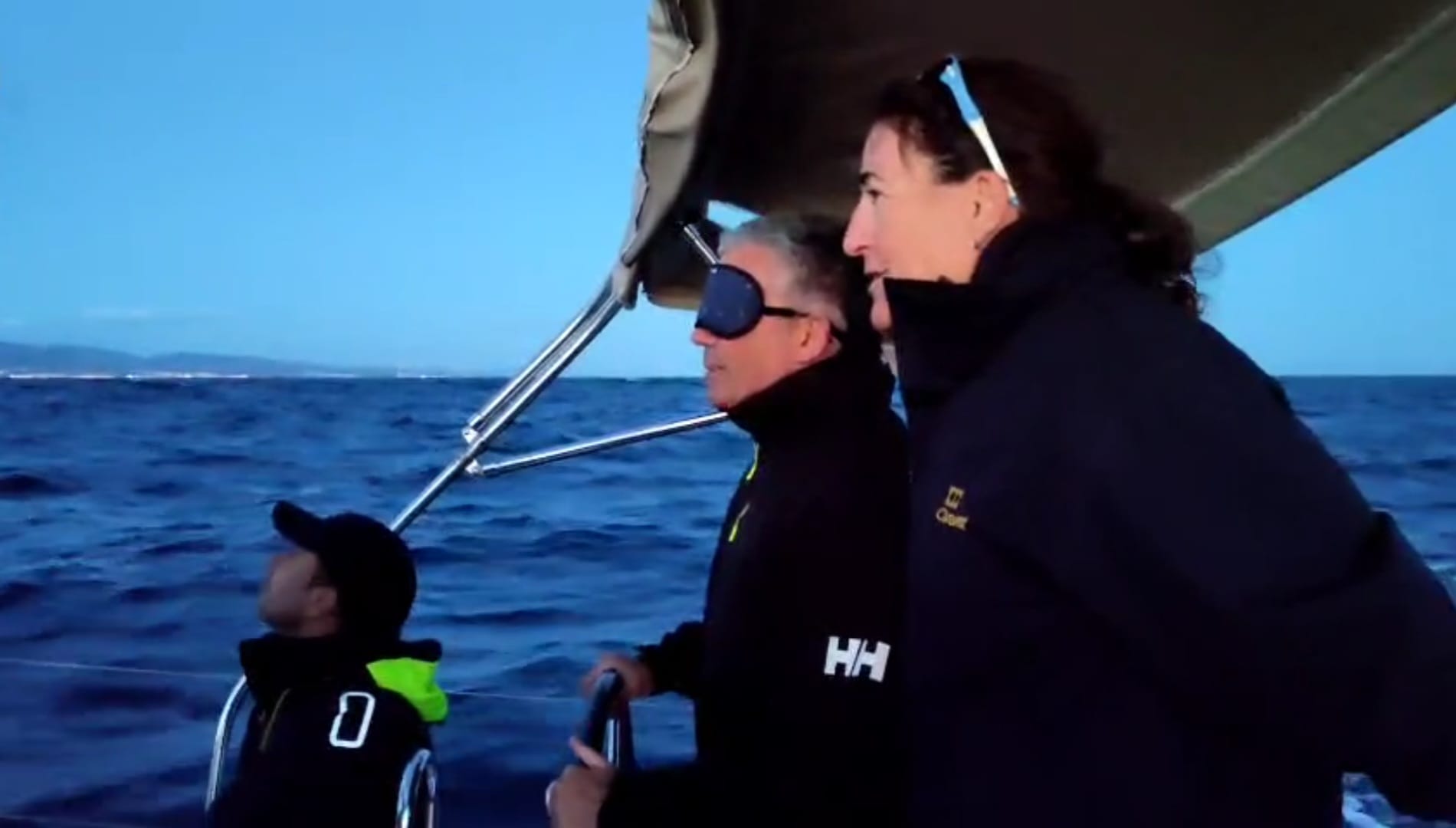 Persona en el timón de barco de vela con antifaz en los ojos
